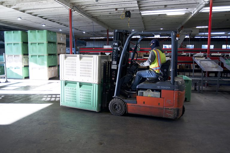 a man driving a loaded pallet truck